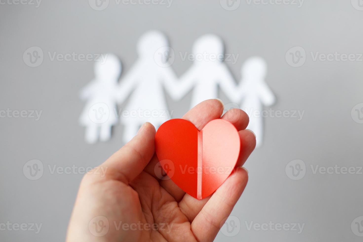 hand innehav röd hjärta på bakgrund av papper skära familj foto