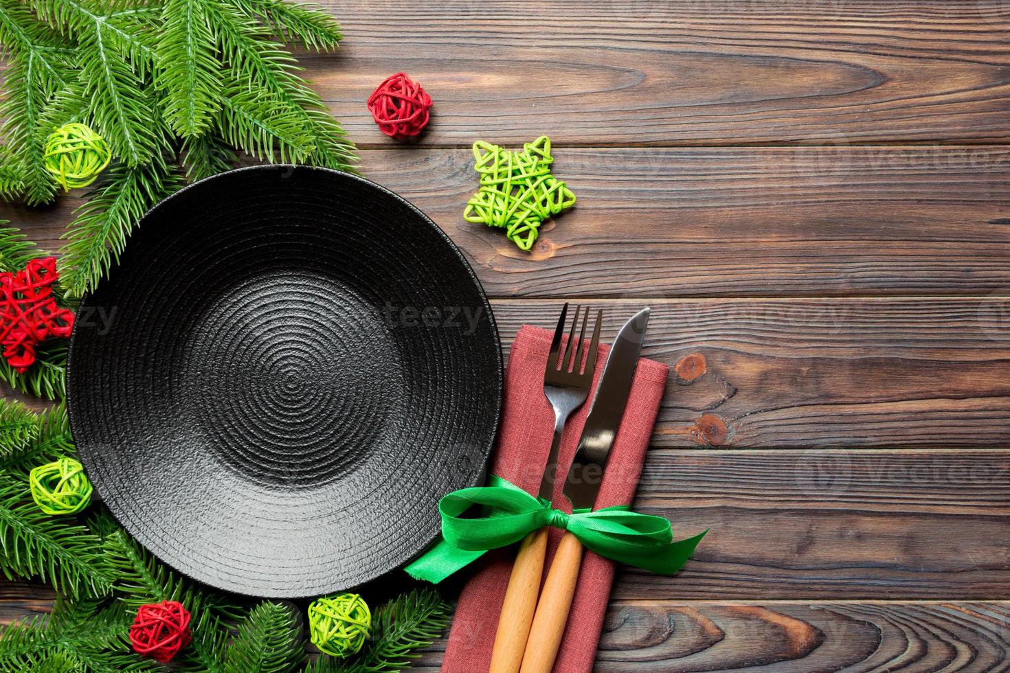 topp se av ny år middag på festlig trä- bakgrund. sammansättning av tallrik, gaffel, kniv, gran träd och dekorationer. glad jul begrepp foto