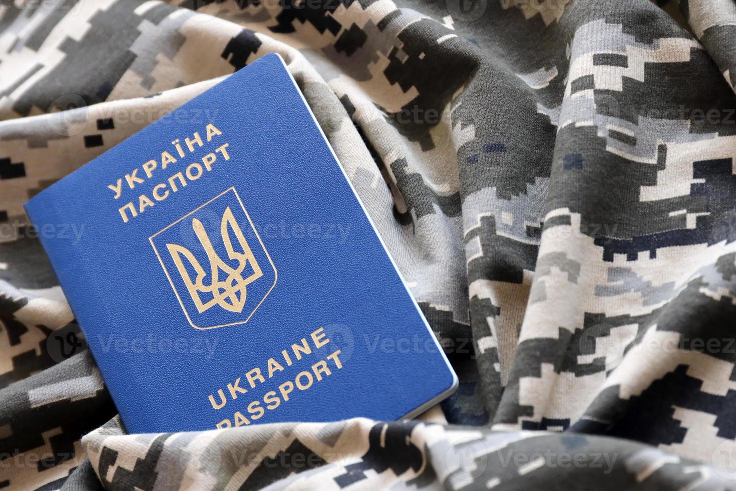 ukrainska utländsk pass på tyg med textur av militär pixeled kamouflage. trasa med camo mönster i grå, brun och grön pixel former och ukrainska id foto
