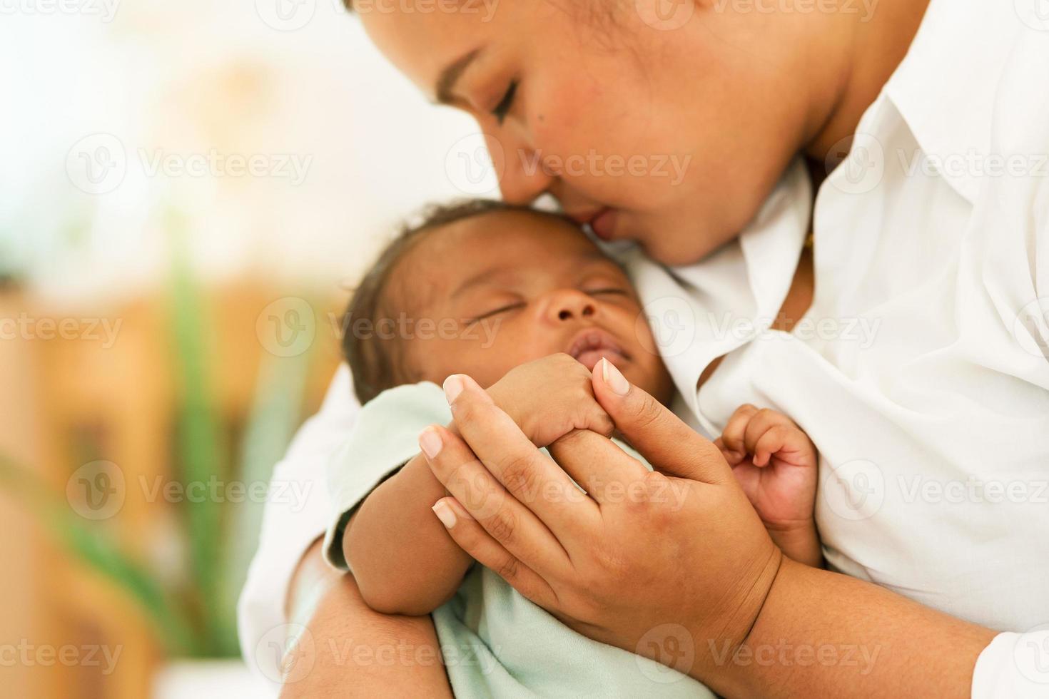 afrikansk nyfödd bebis en månad gammal innehav fingrar mors hand, sömn koppla av oroande i värma omfamning mamma. bild med en grund djup av fält, Välj fokus område hand. begrepp familj blandad lopp. foto