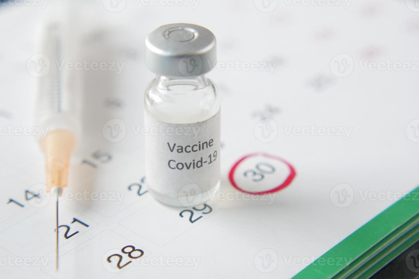 vaccindagskonceptglasampull med vaccin och spruta i kalendern foto