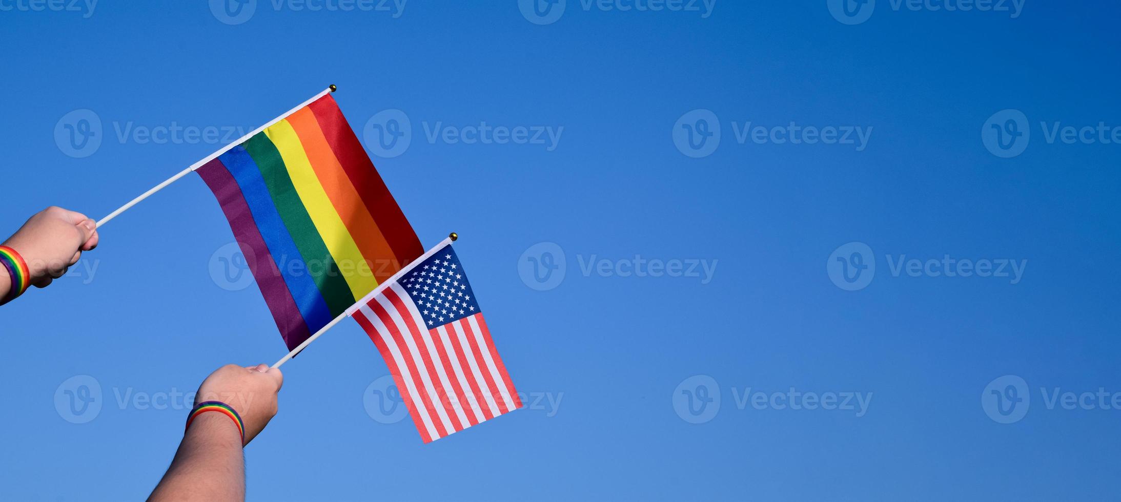 amerikan flagga och regnbåge flagga höjning i händer och mot blå himmel, mjuk och selektiv fokus, begrepp för HBTQ fester och HBTQ evenemang i stolthet månad i usa. foto