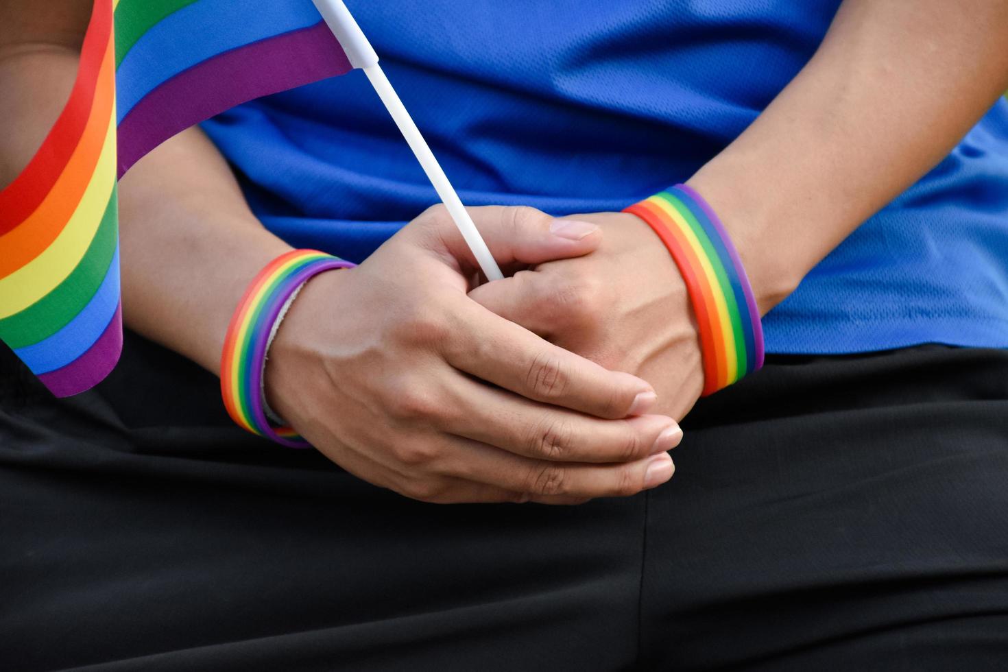 regnbåge flagga hålning i hand av asiatisk Gay som bär regnbåge handledsband till ring upp ut och visar HBTQ kön mångfald och respekterar kön alternativ runt om de värld. foto