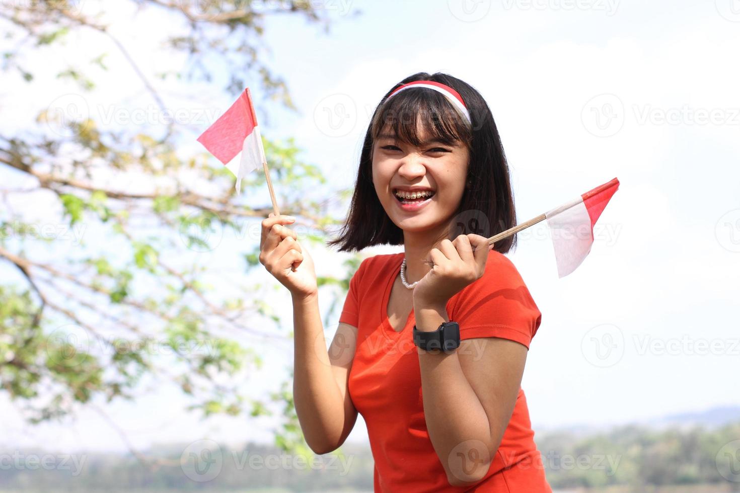 skön ung asiatisk kvinna bärande de indonesiska flagga med en glad ansikte foto