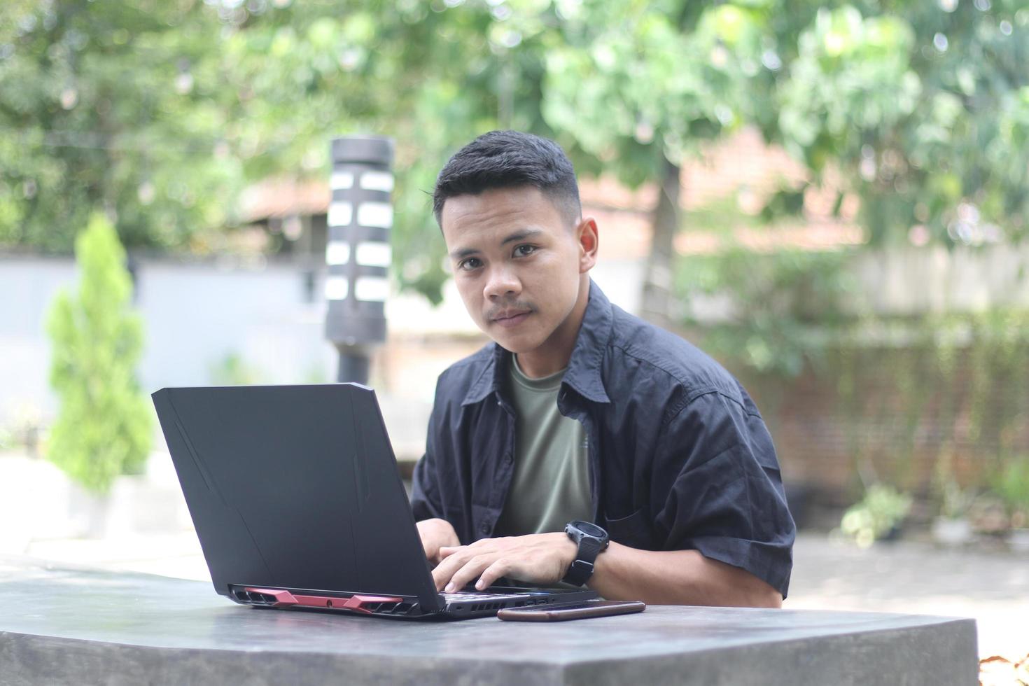 attraktiv ung asiatisk man använder sig av bärbar dator i sam-arbetande Plats med Lycklig ansikte foto