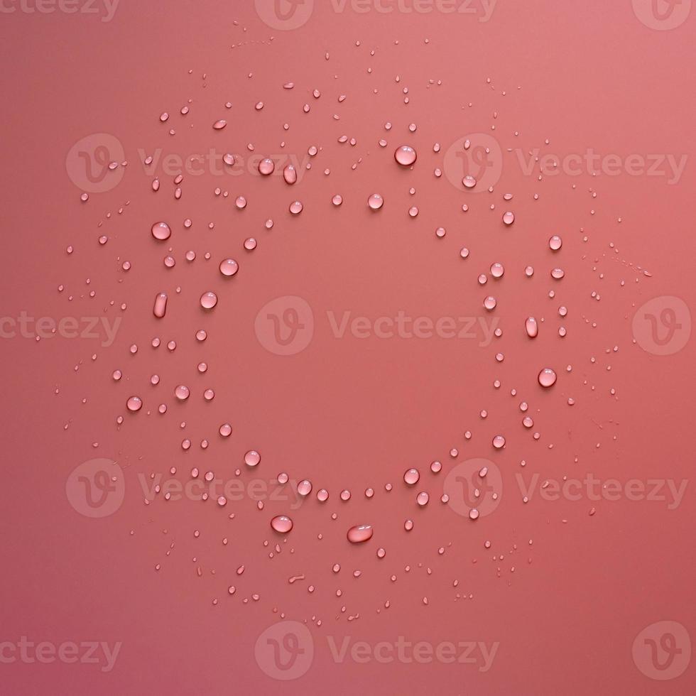 droppar av vatten i de form av en cirkel på en rosa bakgrund. kopia Plats. topp se. foto