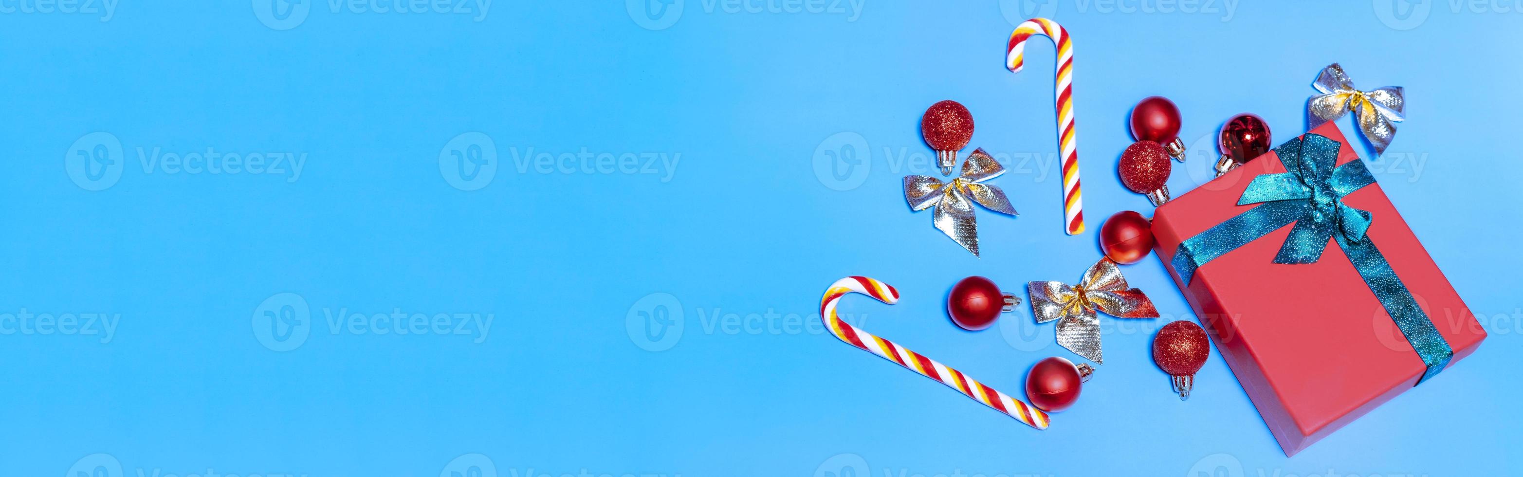 baner av skön jul röd bollar och en röd gåva med en grön band, med klubbor på en blå bakgrund. ny år jul begrepp. platt lägga festlig attrapp med kopia Plats foto