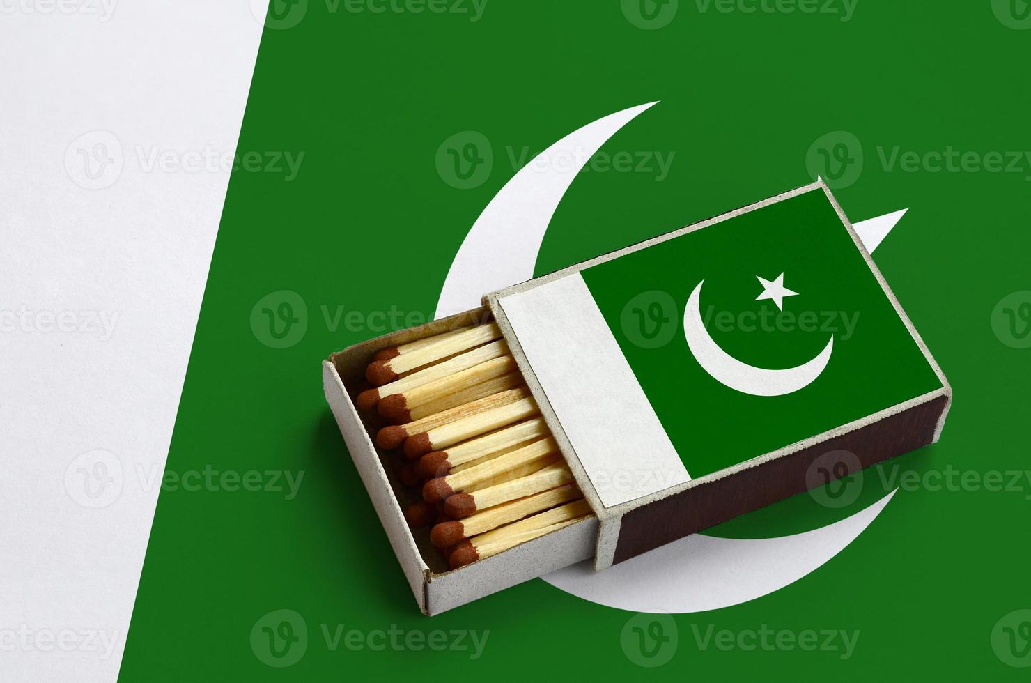 pakistan flagga är visad i ett öppen tändsticksask, som är fylld med tändstickor och lögner på en stor flagga foto
