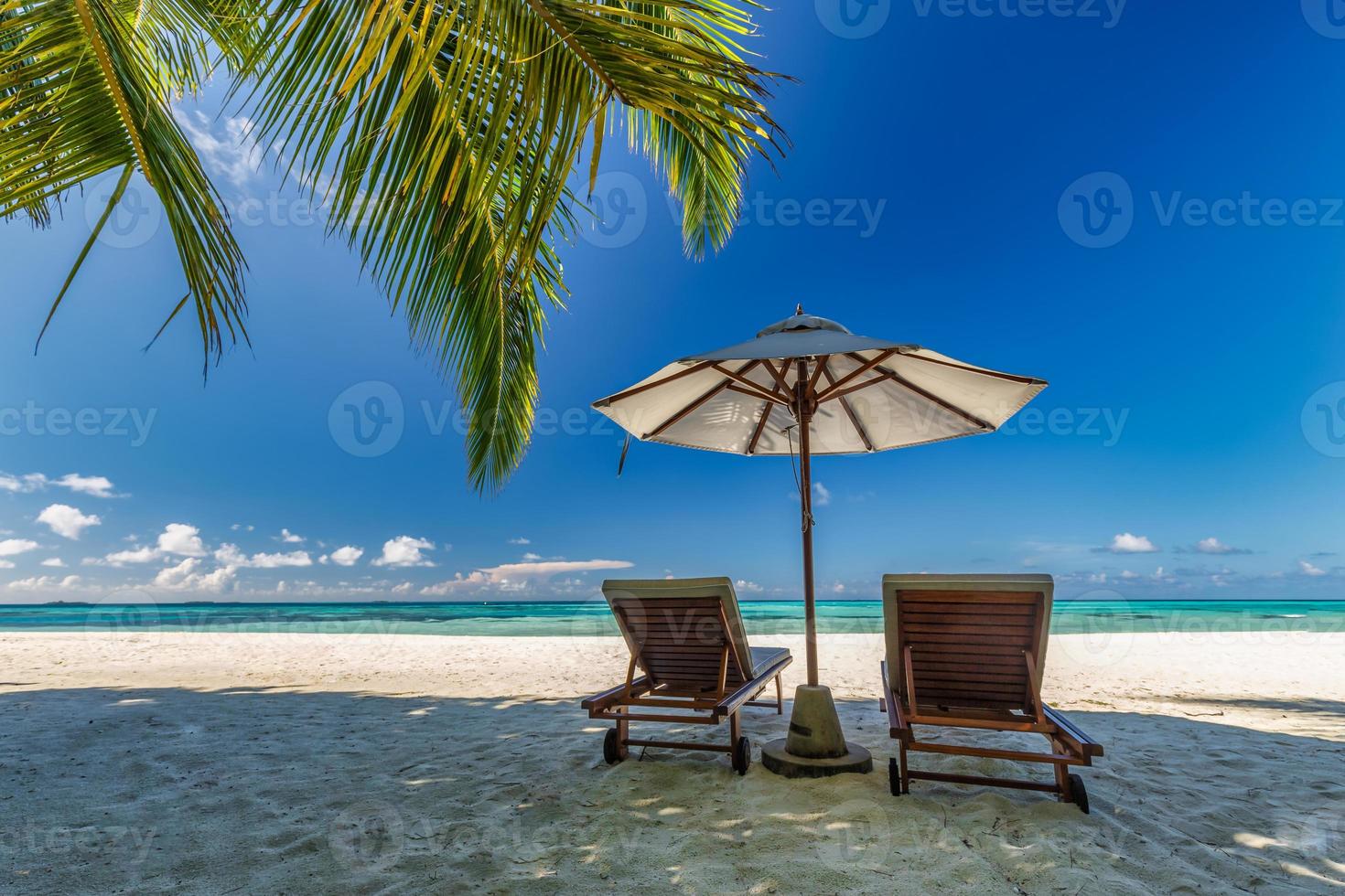 skön tropisk solig Strand, par Sol sängar stolar paraply under handflatan träd löv. hav sand horisont himmel. romantisk koppla av livsstil inspirera ö strand bakgrund. sommar resa exotisk semester foto