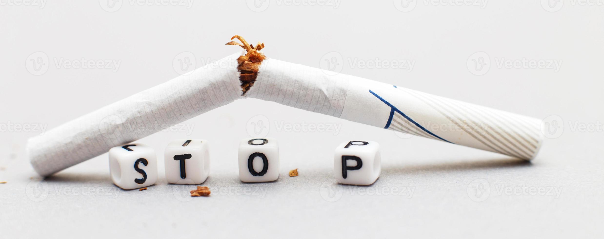 bruten cigarett med de ord sluta på grå bakgrund stänga. sluta rökning begrepp. baner foto