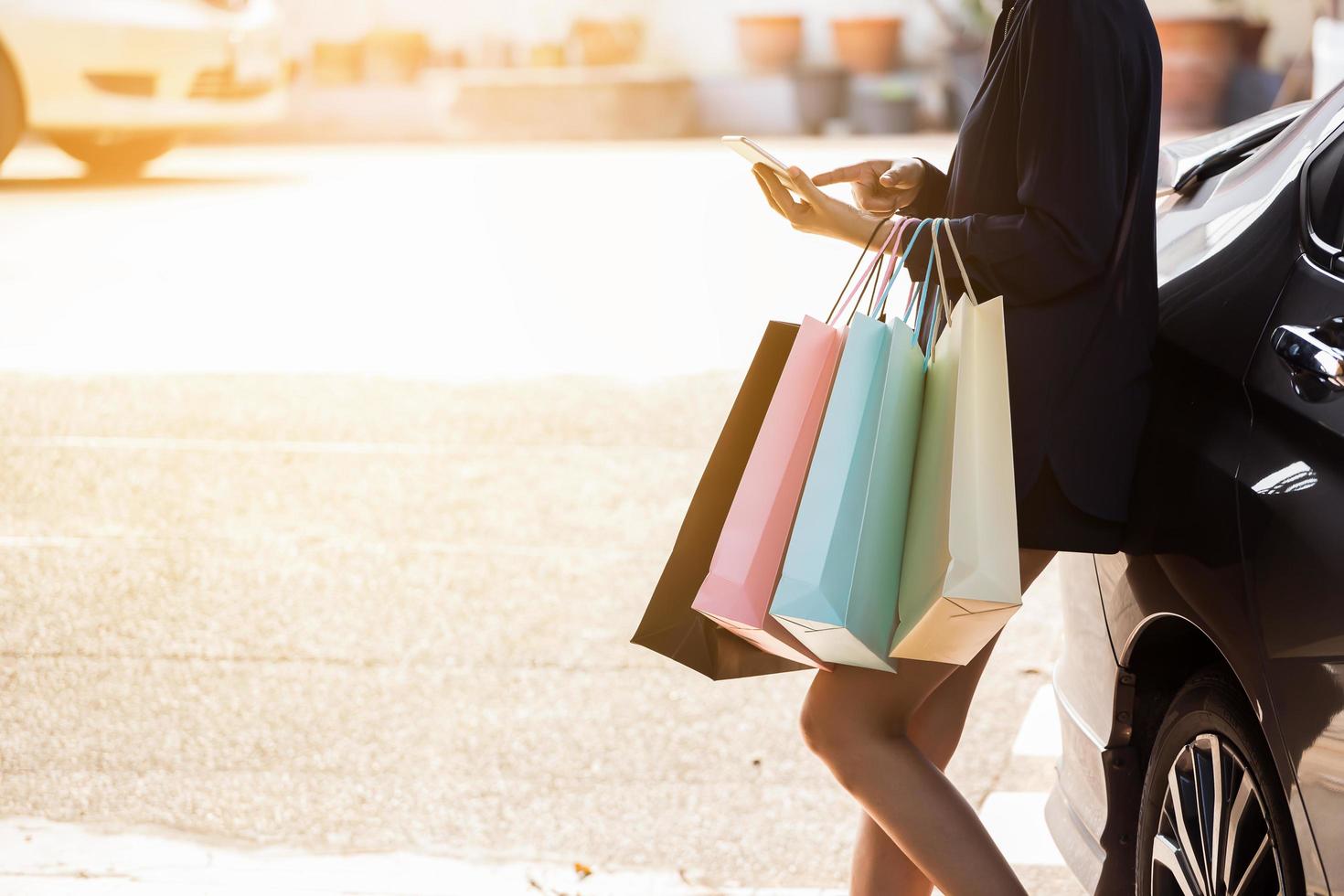 person som använder smarta telefonen som håller shoppingkassar foto