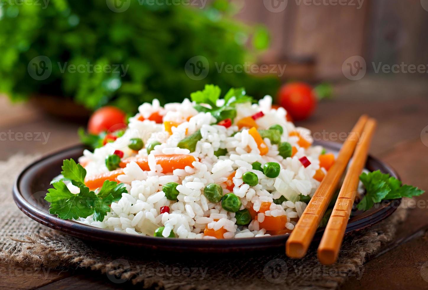 aptitlig friska ris med grönsaker i vit tallrik på en trä- bakgrund. foto