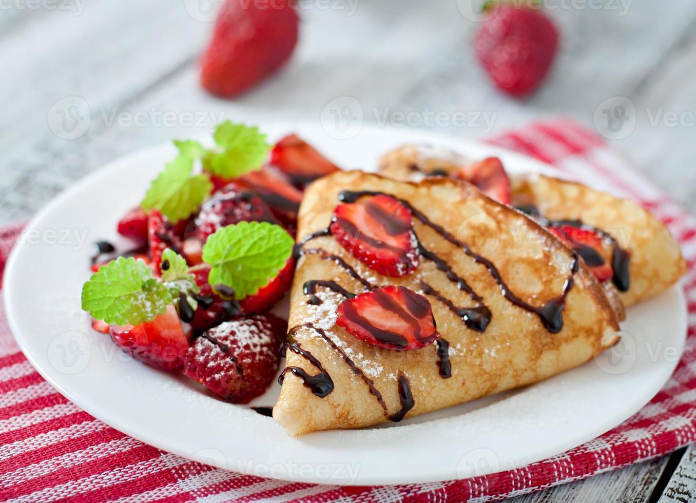 pannkakor med jordgubbar och choklad dekorerad med mynta blad foto