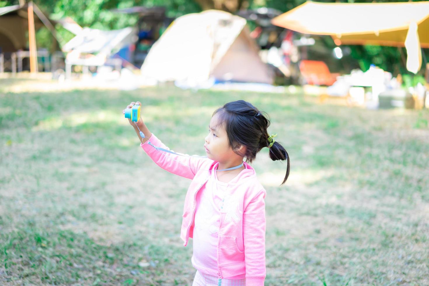 porträtt av söt liten asiatisk tjej som har kul med en leksakskamera foto