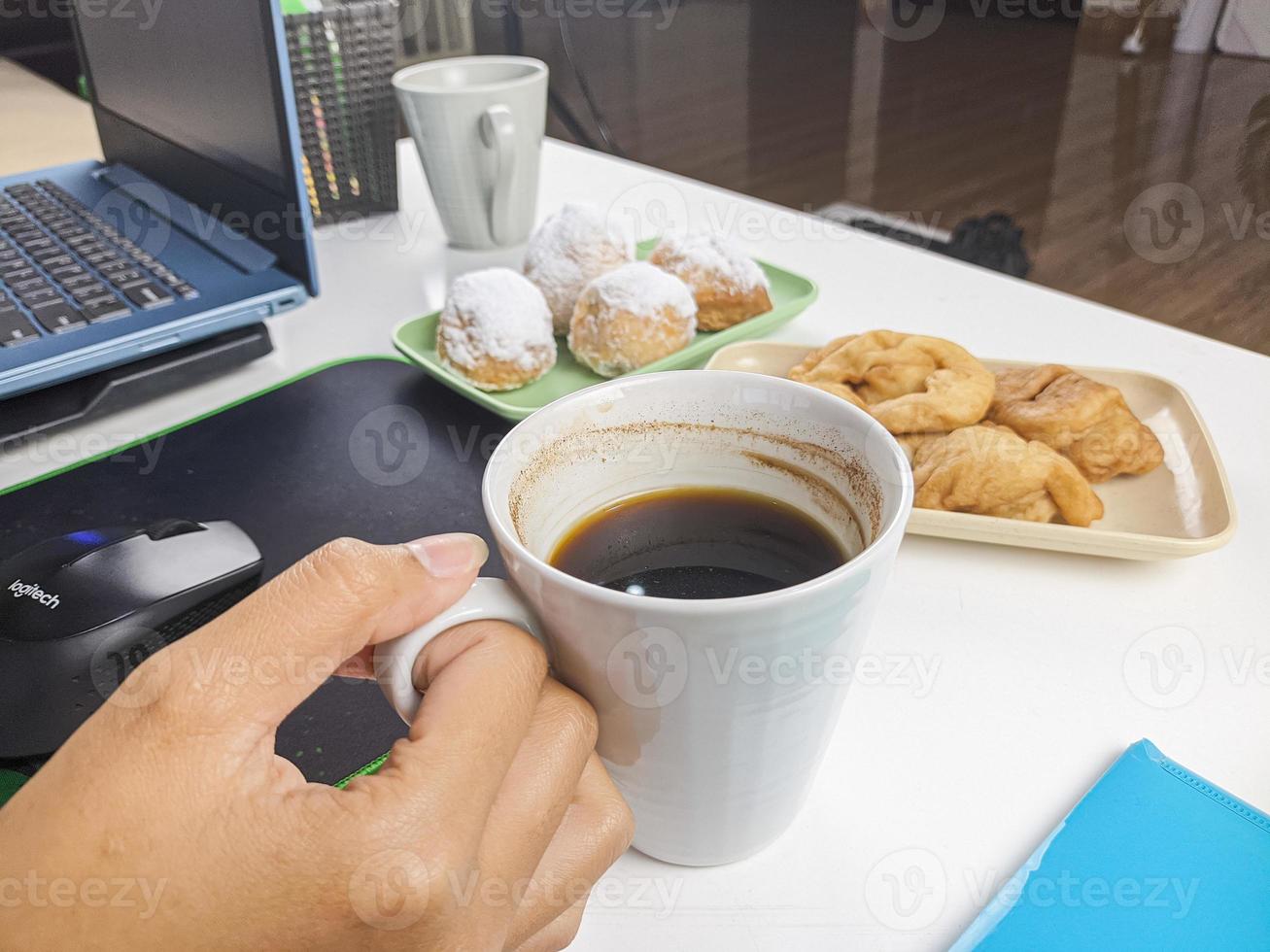 en ung kvinna drack en glas av kaffe åtföljs förbi snacks under bryter under arbete tid. foto