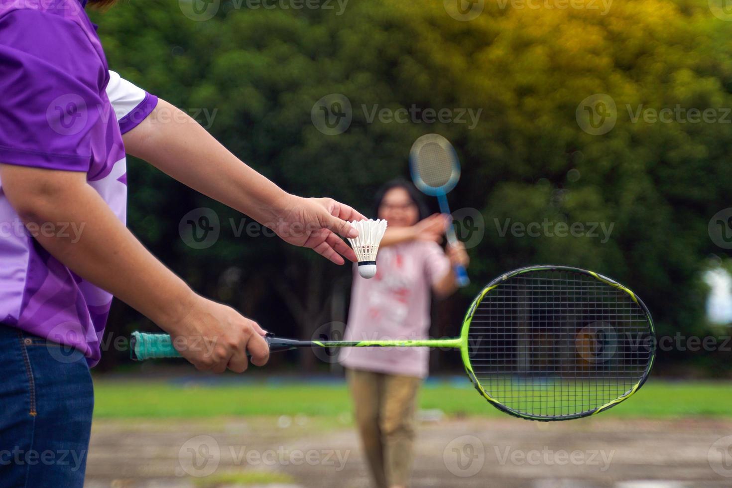 asiatisk kvinna och henne vän badminton spelare spela badminton tillsammans efter arbete på gård på arbete. begrepp, en fritid aktivitet till do varje dag efter arbete, mjuk och selektiv fokus. foto