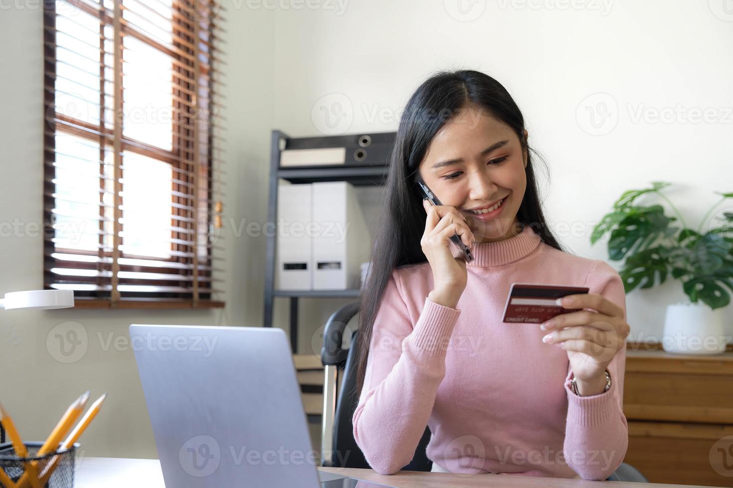 Lycklig asiatisk företag kvinna betala uppkopplad använder sig av mobil telefon på de kontor. foto