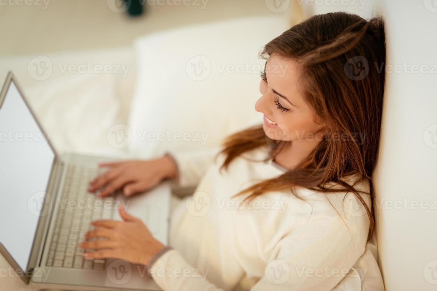 kvinna använder sig av bärbar dator i säng foto