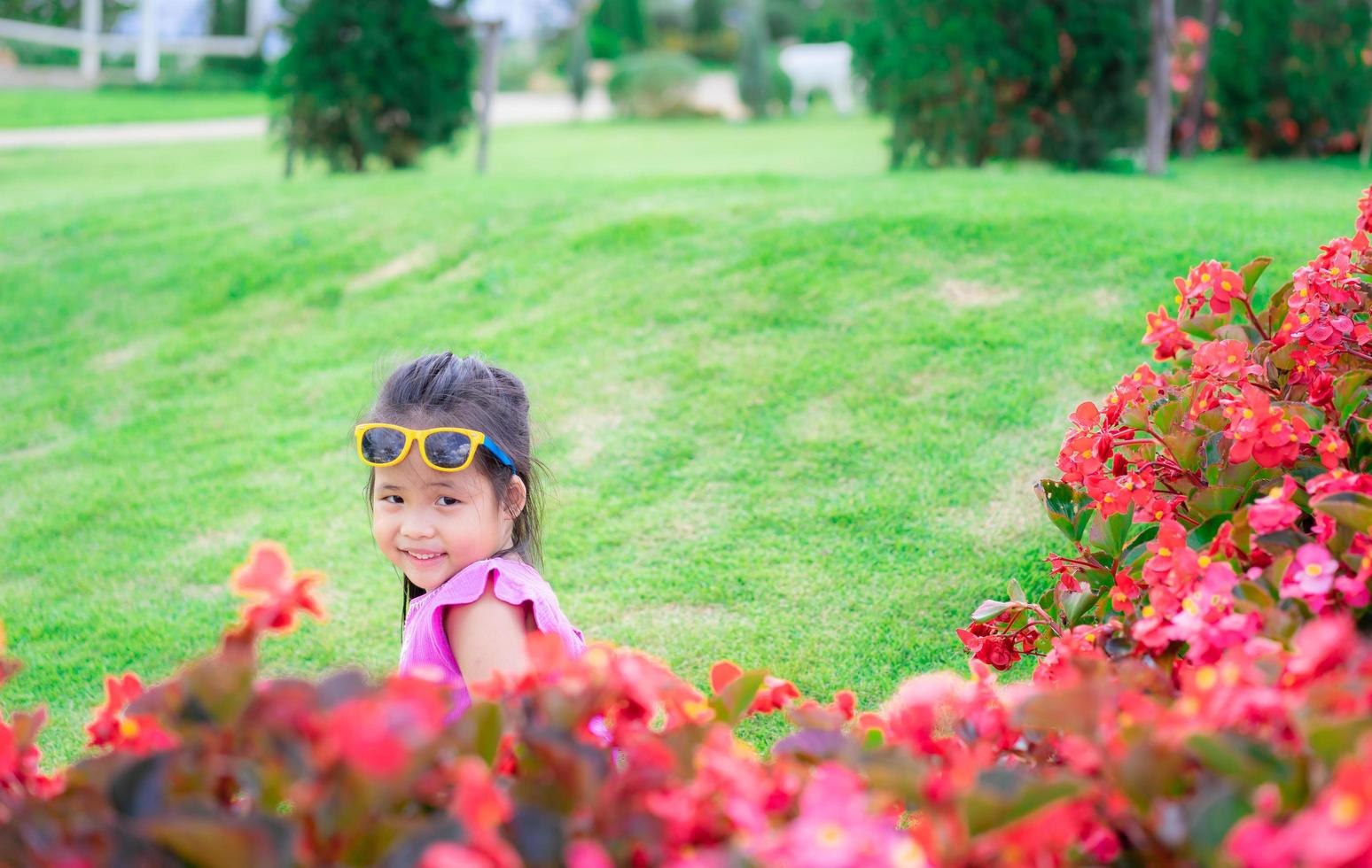 asiatisk tjej i rosa klänning som sitter på marken i blomsterträdgård foto