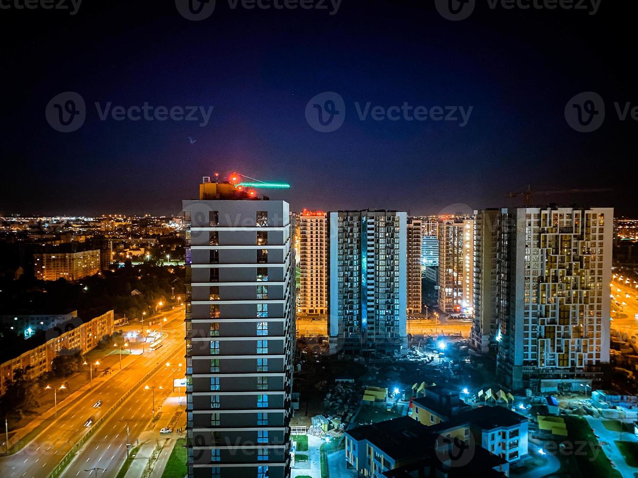 se av de natt stad från en höjd. lång hus med panorama- fönster och målad fasader. flygplan varning på de hus foto