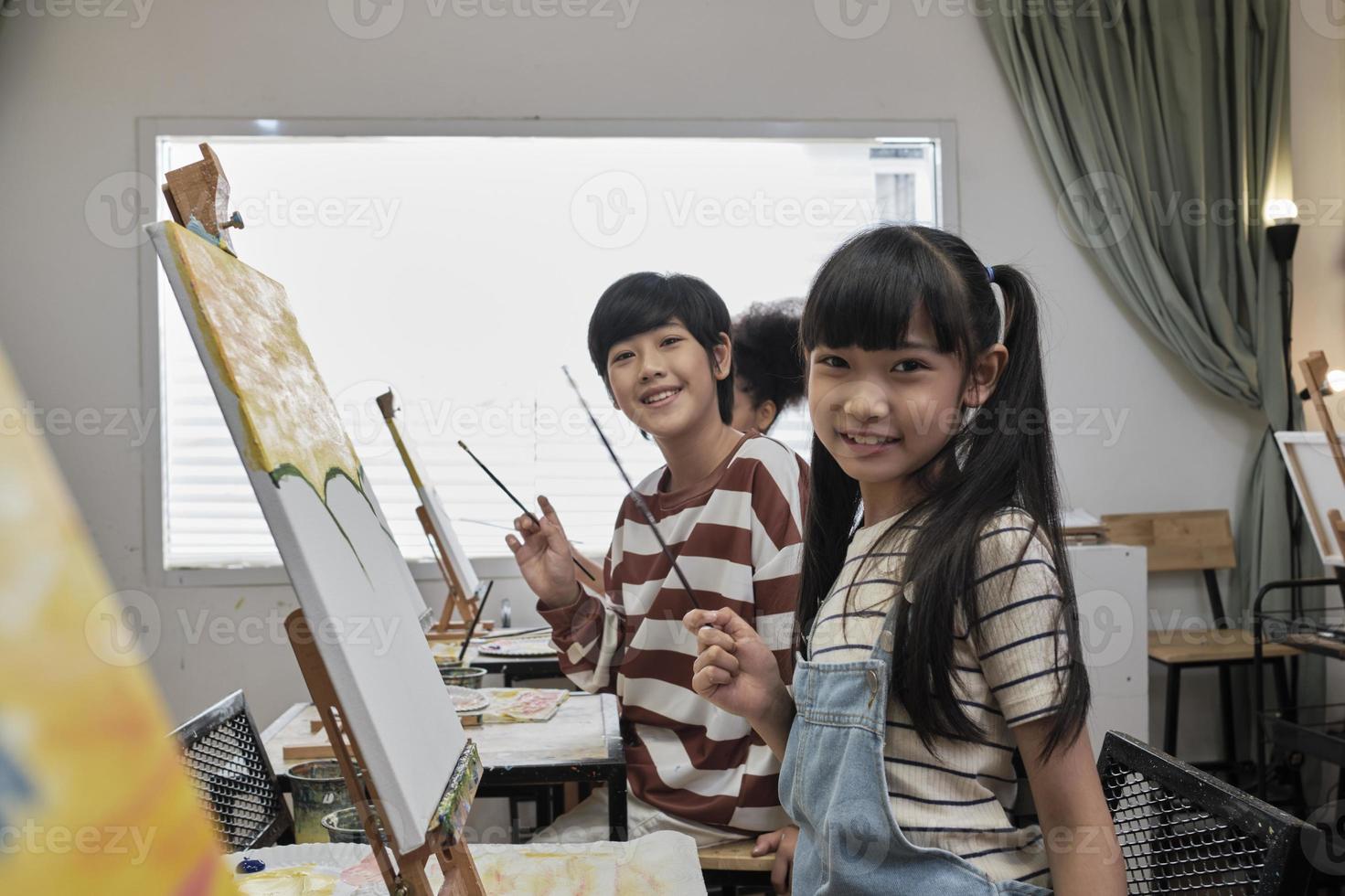 porträtt av asiatisk barn ser på kamera och leende med akryl Färg bild målad på duk i konst klassrum och kreativ inlärning med talanger och skicklighet på elementärt skola studio utbildning. foto