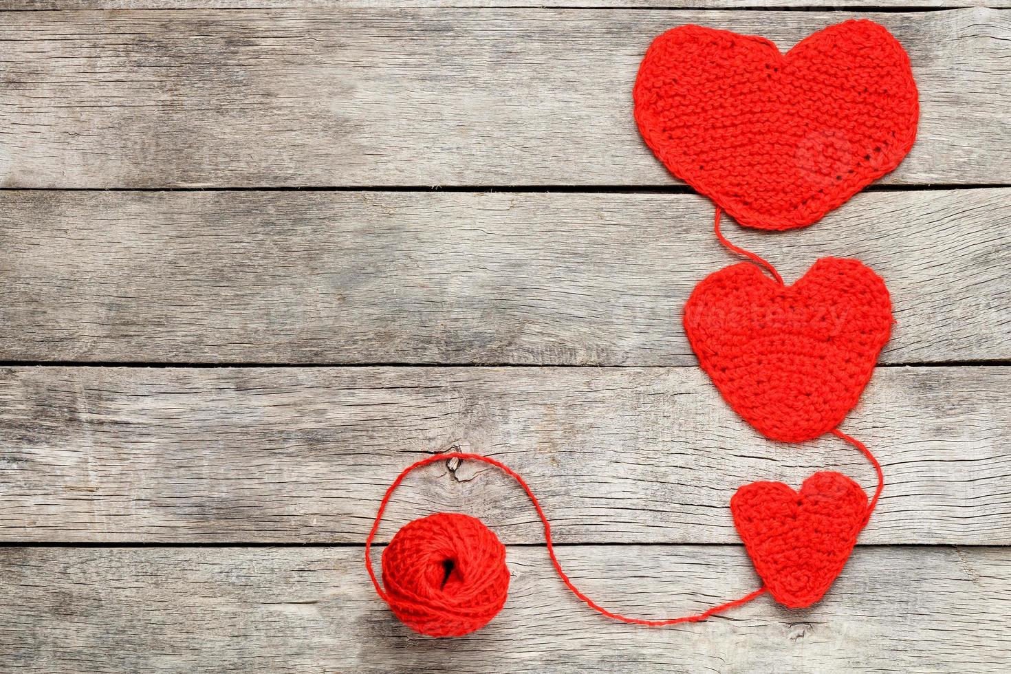 tre röd stickat hjärtan på en grå trä- bakgrund, symboliserar kärlek och familj. familj relation, obligationer. foto