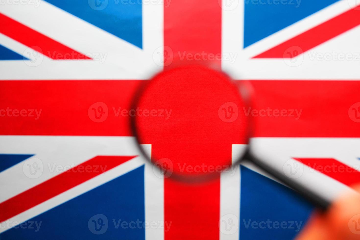 Storbritannien flagga ser genom en förstorande glas. total övervakning av de Land av england. de begrepp av dold hot och kontrollera över de Land foto