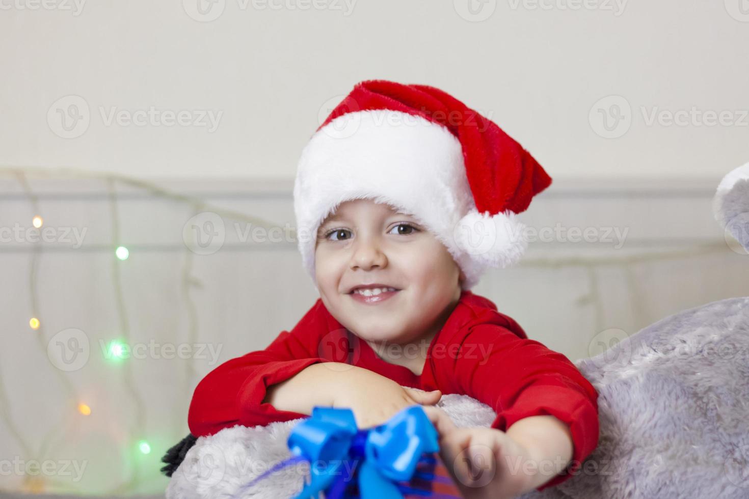 porträtt av en söt pojke i en santa claus hatt. rolig leende barn. foto