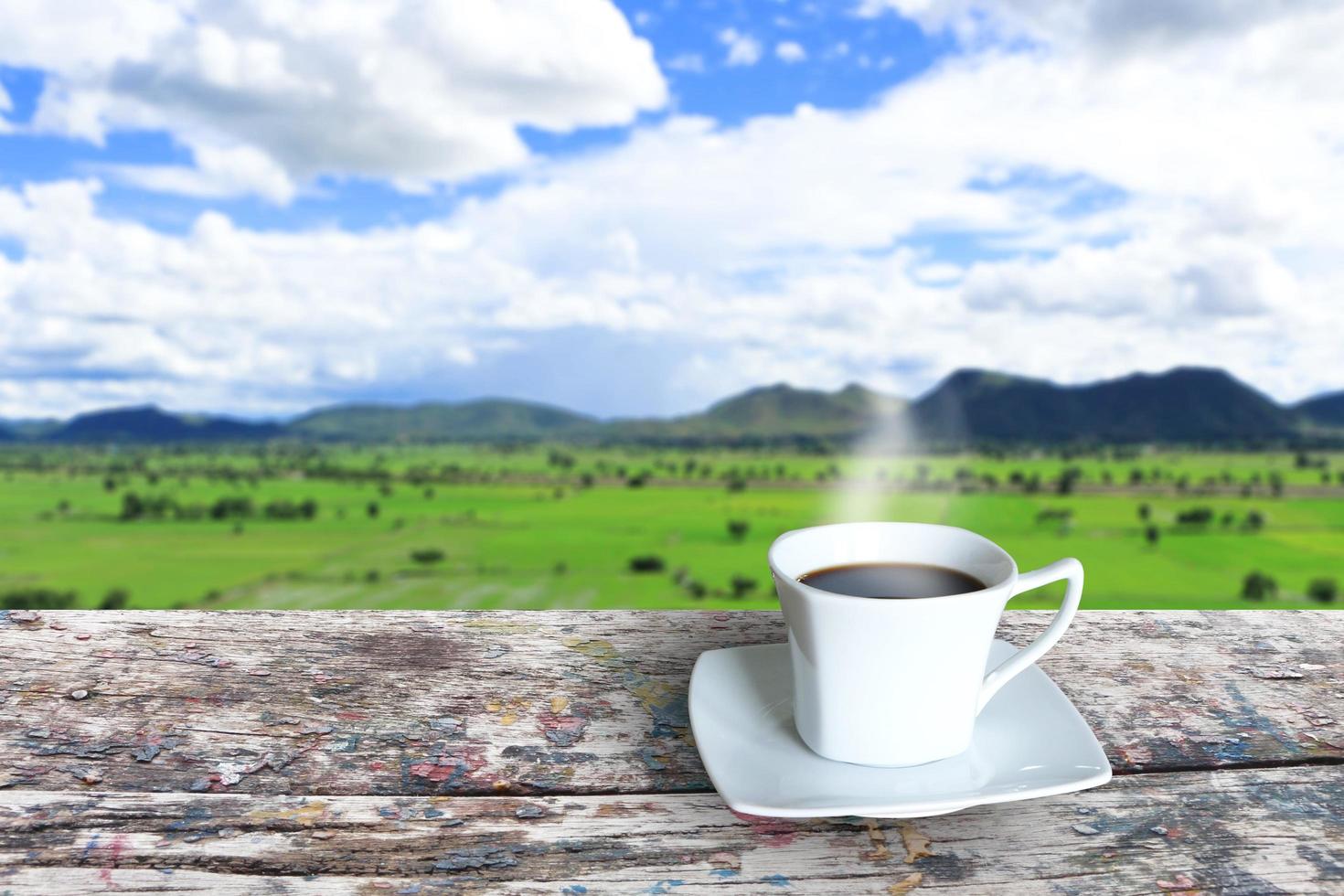varm kaffe kopp på de trä- tabell eller balkong i främre av ris fält och bergen i de morgon- med en kopia Plats. foto