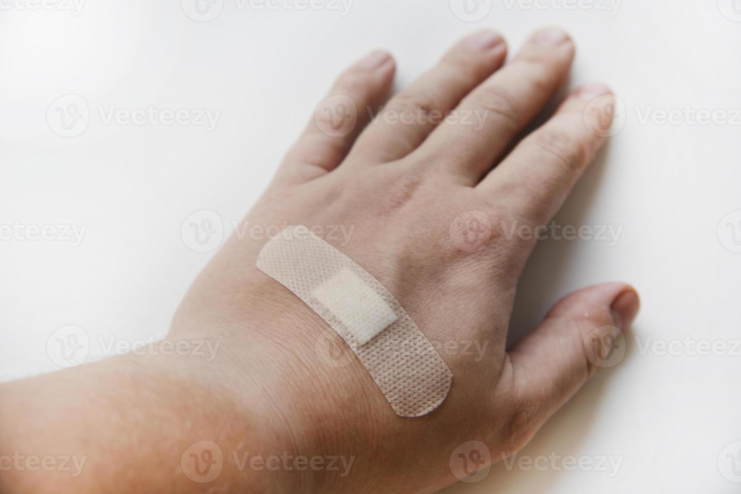 en medicinsk lappa på en mannens ärm på en vit bakgrund. en gul lappa på de sår på hans ärm. foto