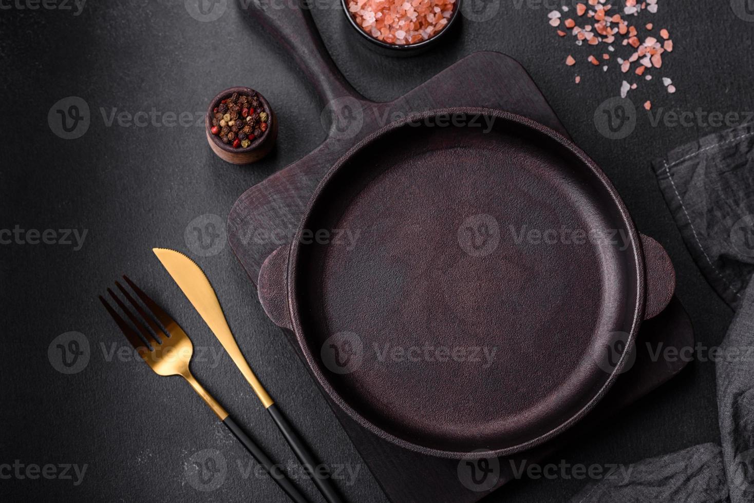 brun järn tömma panorera med kök redskap på en mörk betong bakgrund foto