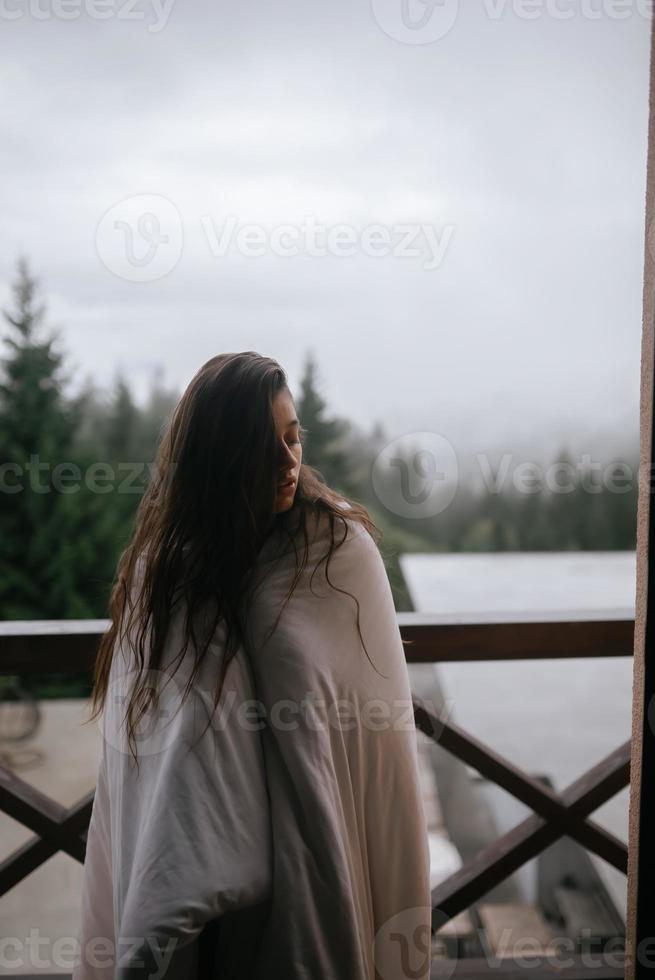 ung kvinna insvept i en filt på de balkong foto