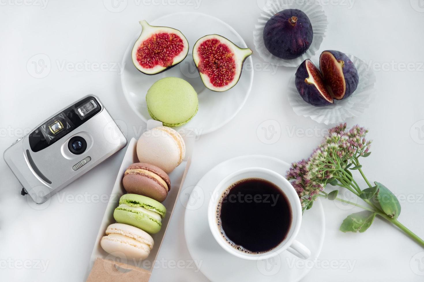 estetisk filma kamera flatlay, koppar av kaffe, fikon och macarons på en vit bakgrund, topp se foto