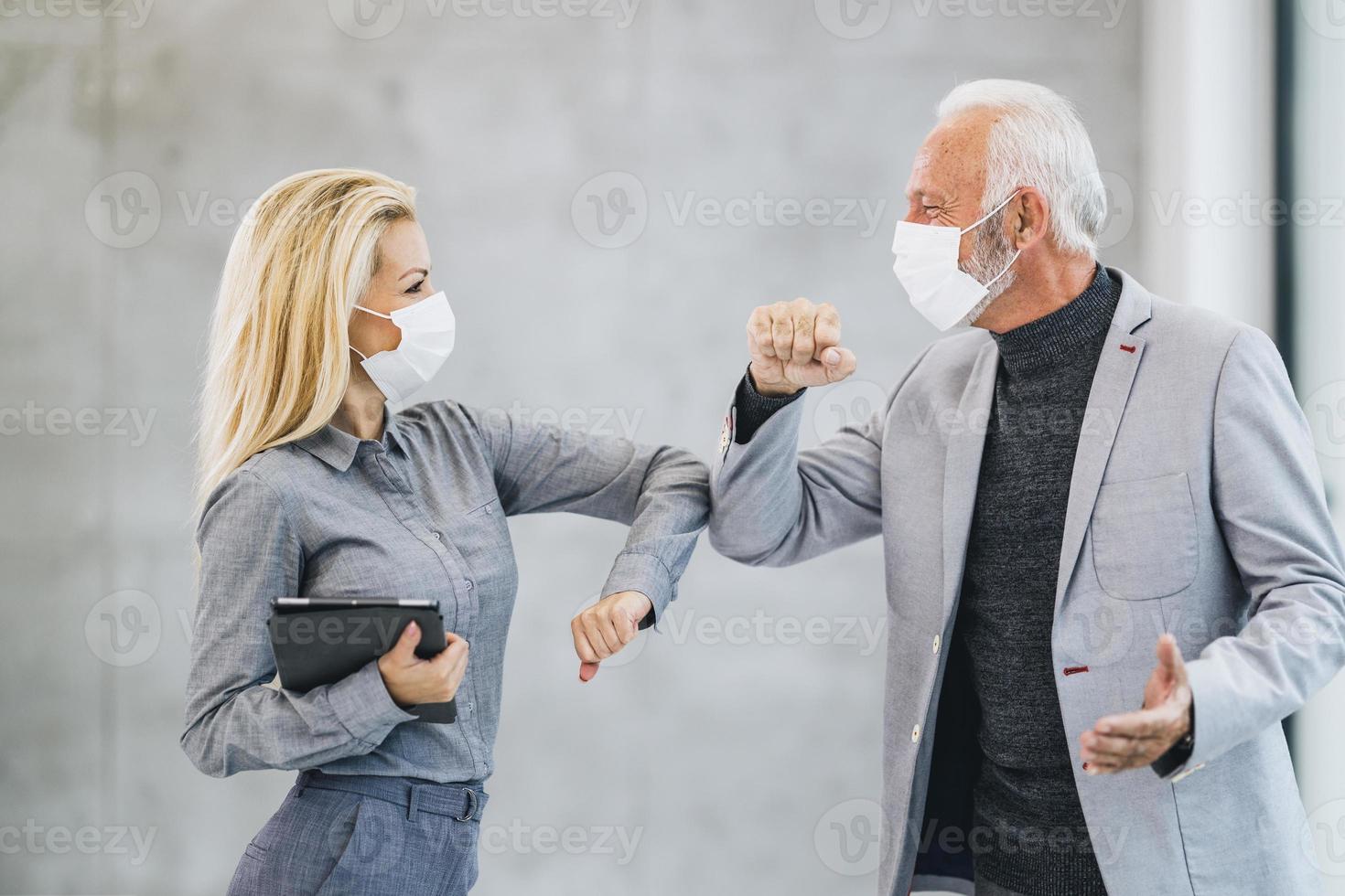 två företag person hälsning med skumpande armbågar under coronavirus pandemi i de kontor foto