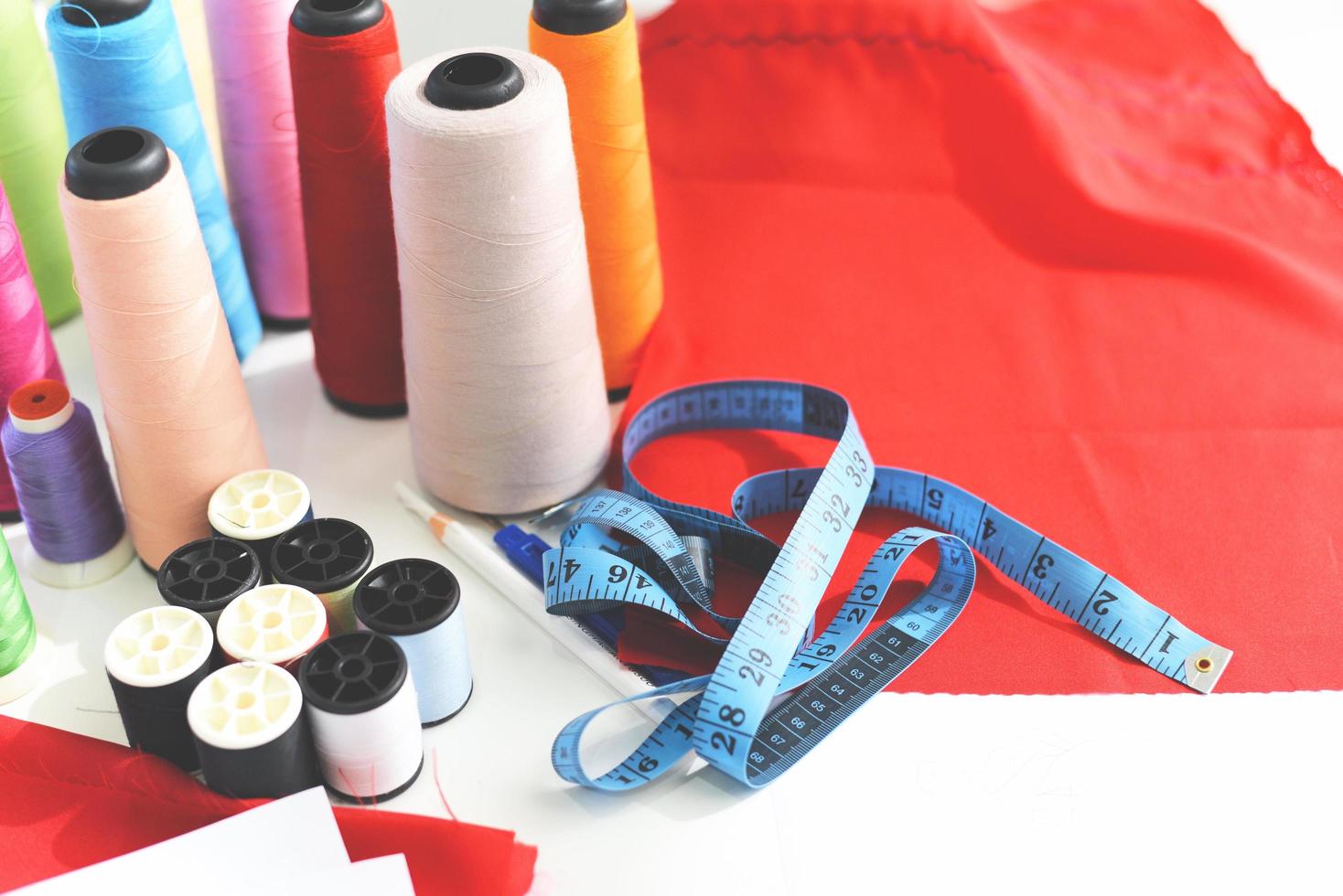 verktyg hantverk mätning tejp sömnad tråd och nål tråd för mode designer i studio textil- material sax skärande tyg kläder sömnad maskin designer arbetssätt foto