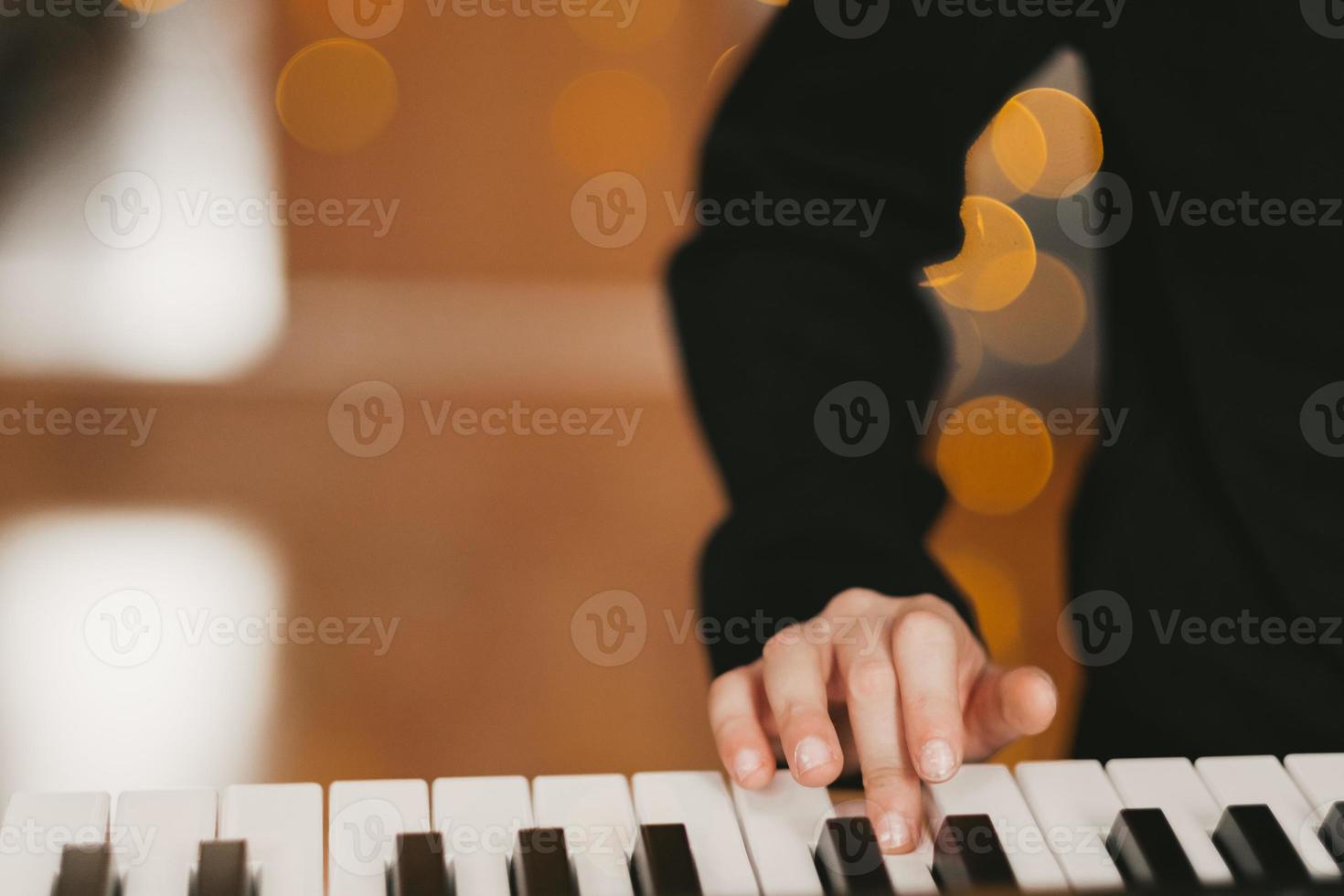 en barnets hand spelar de digital piano, mot de bakgrund av en jul krans. de barn spelar de synthesizer. barnets musikalisk hobby. de kreativ bearbeta på Hem. foto