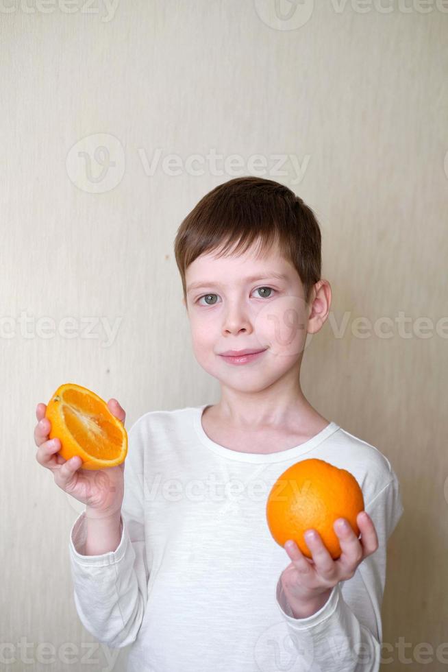 Lycklig leende pojke med vitamin c och orange i händer foto