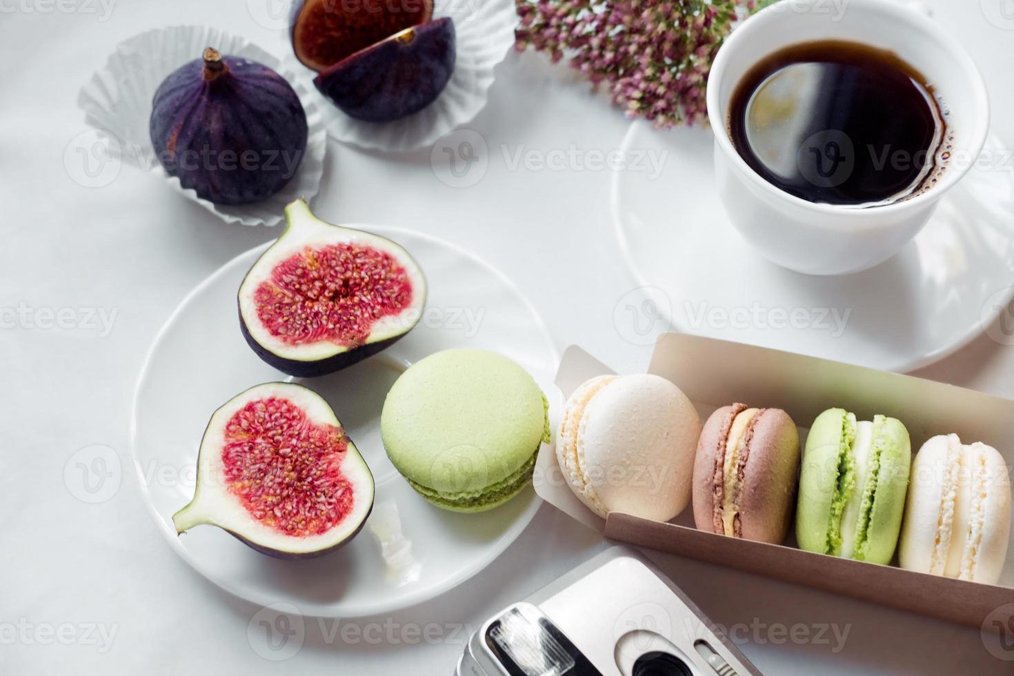 estetisk filma kamera flatlay, koppar av kaffe, fikon och macarons på en vit bakgrund, topp se foto