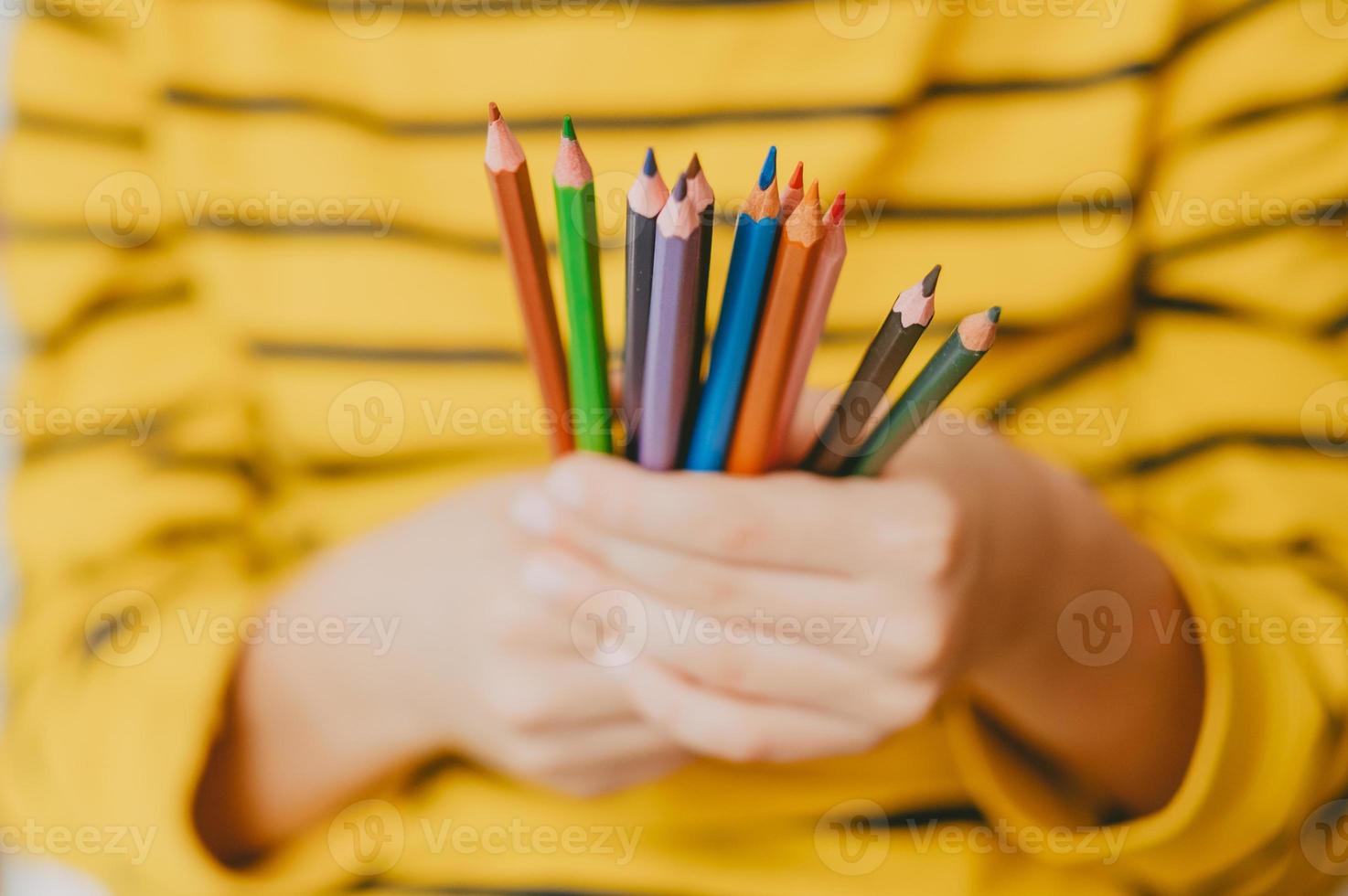 färgad pennor i de händer av en liten pojke. ljus Foto med pennor för teckning. med skoltema fotografi