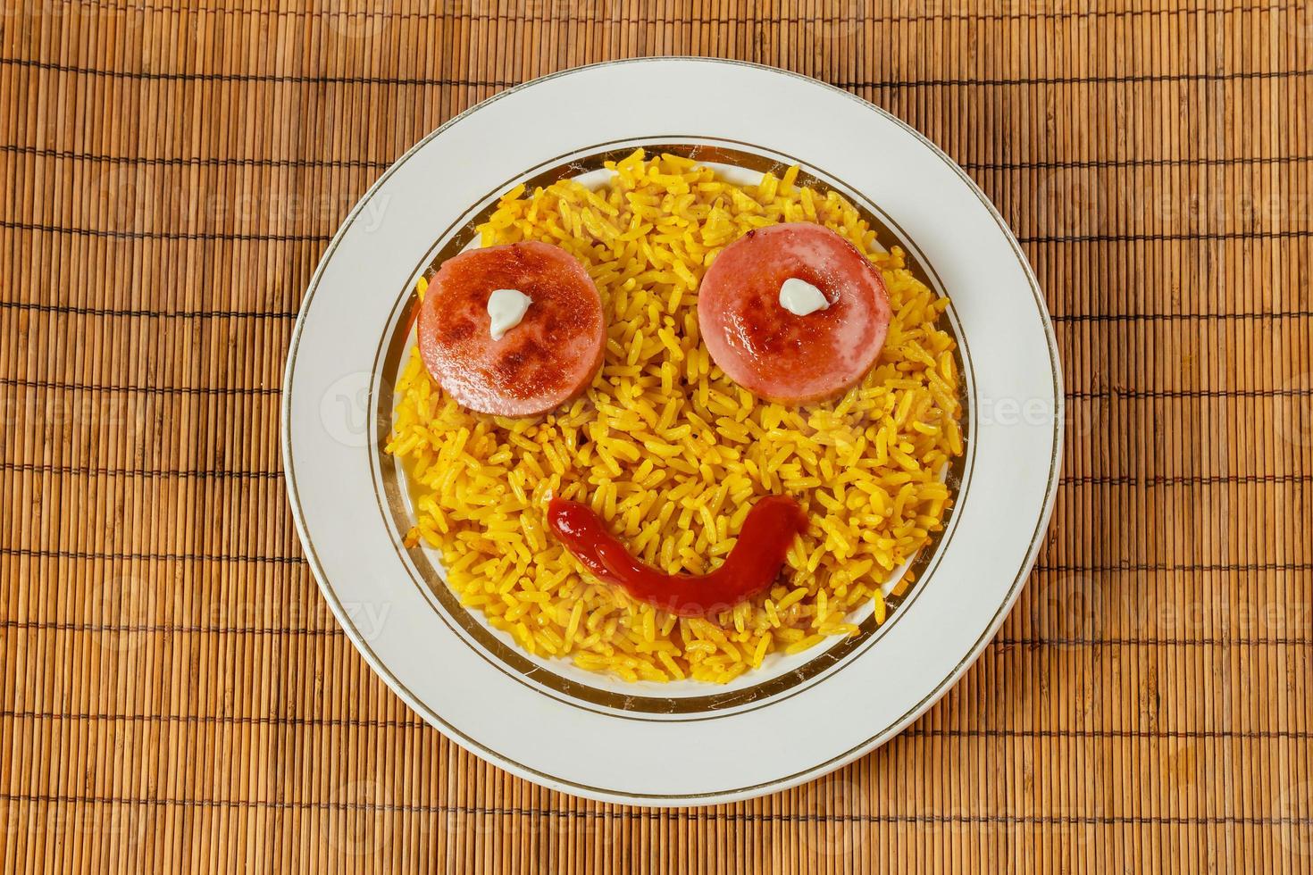 gul ris på en tallrik med korv i de form av ögon, roligt mat foto