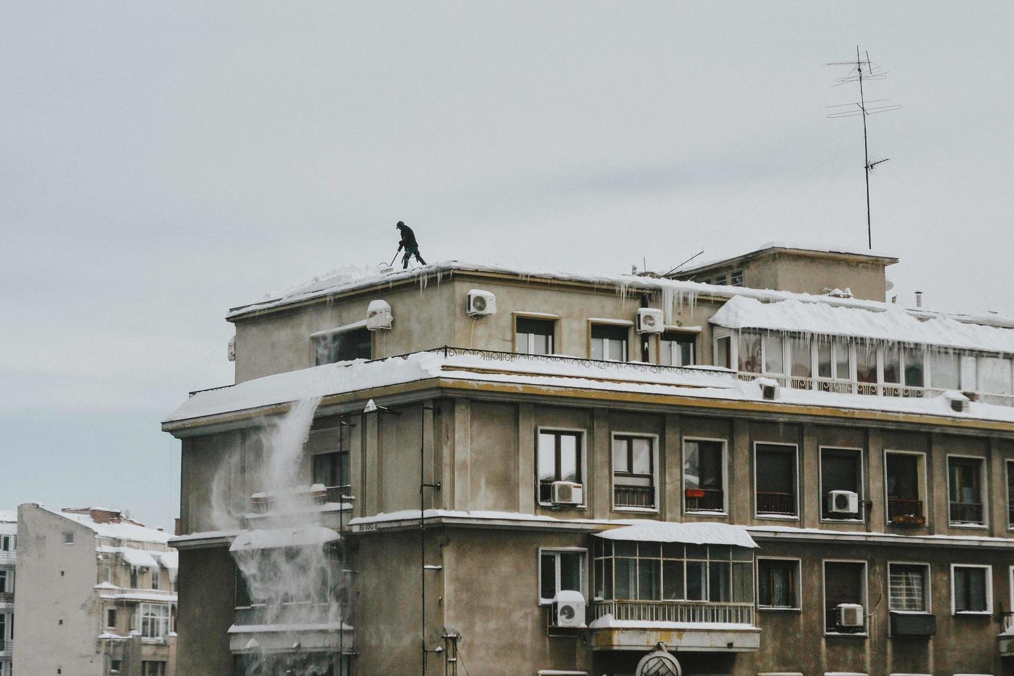 Bukarest, Rumänien, 2020 - man skjuter snö från taket foto