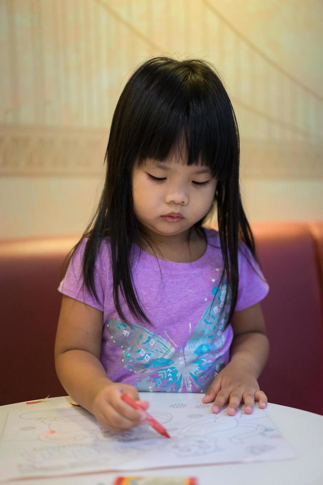 asiatisk tjej sitter och målar en bild i förskolan foto