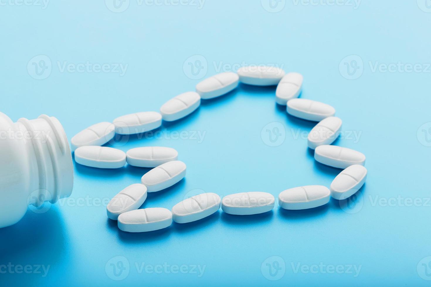 vit vitaminer med kalcium ca, d3 i de form av en tand spridd från en vit burk på en blå bakgrund foto