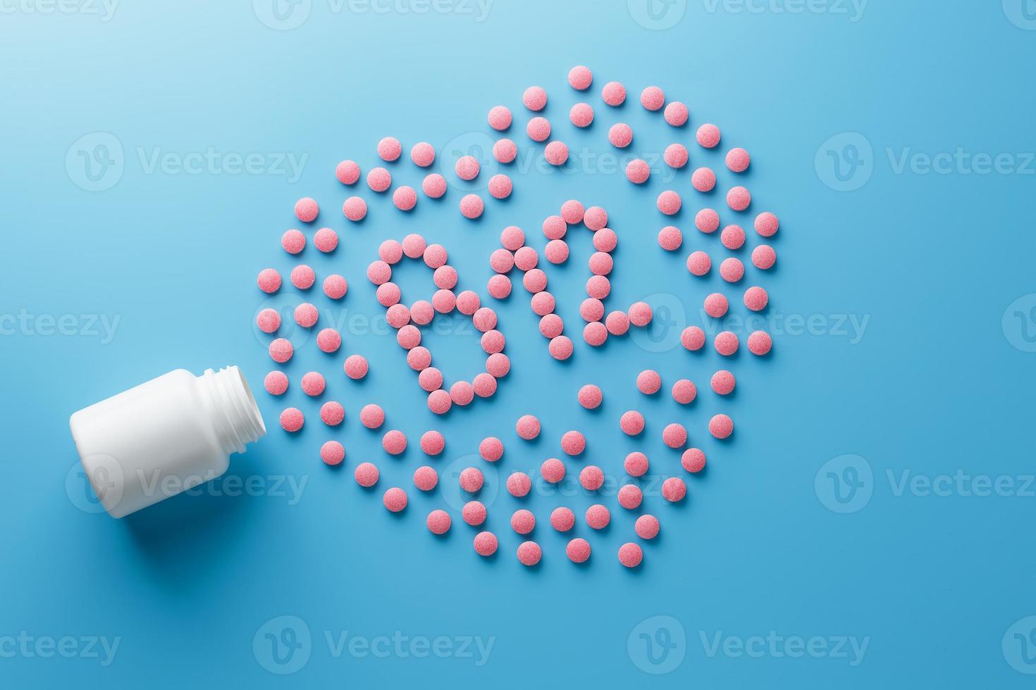 rosa tabletter i de form av b12 i de hjärta på en blå bakgrund, spillts från en vit burk. foto
