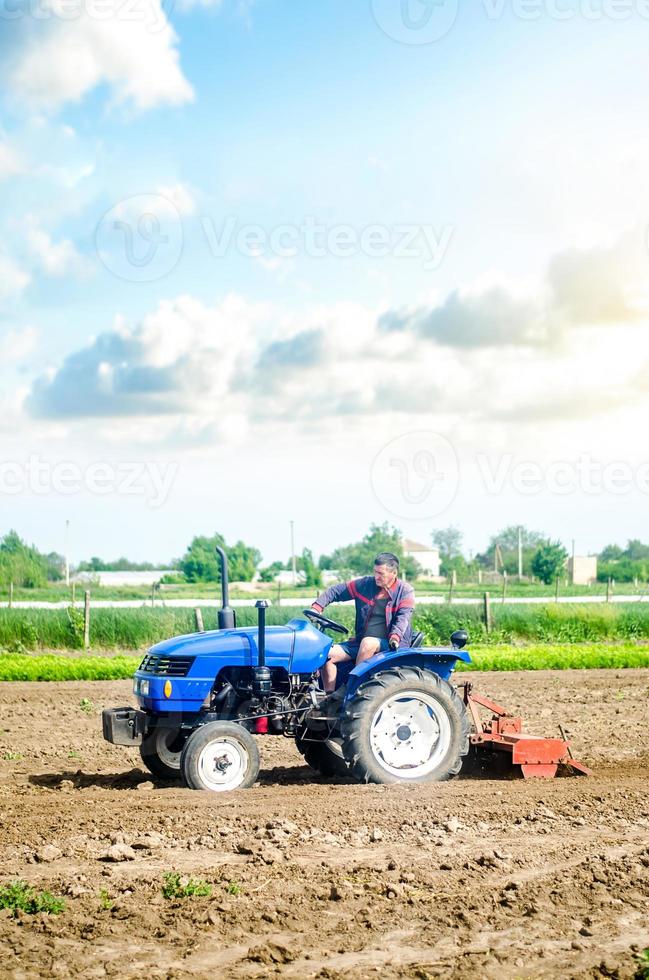 de jordbrukare enheter en traktor med en fräsning enhet Utrustning. lossna landa odling använda sig av av jordbruks maskineri till hastighet upp arbete. jordbruk. plöjning fält. de skede av framställning jord för plantering. foto