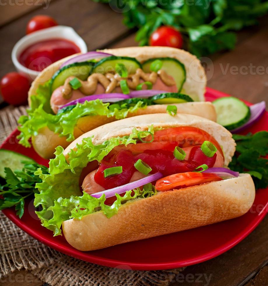 hotdog med ketchup, senap, sallad och grönsaker på träbord foto