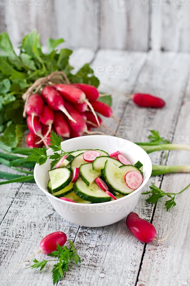 färsk sallad av gurkor och rädisor i en vit skål på de gammal trä- bakgrund foto