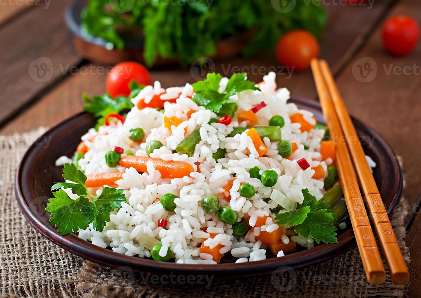 aptitlig friska ris med grönsaker i vit tallrik på en trä- bakgrund. foto