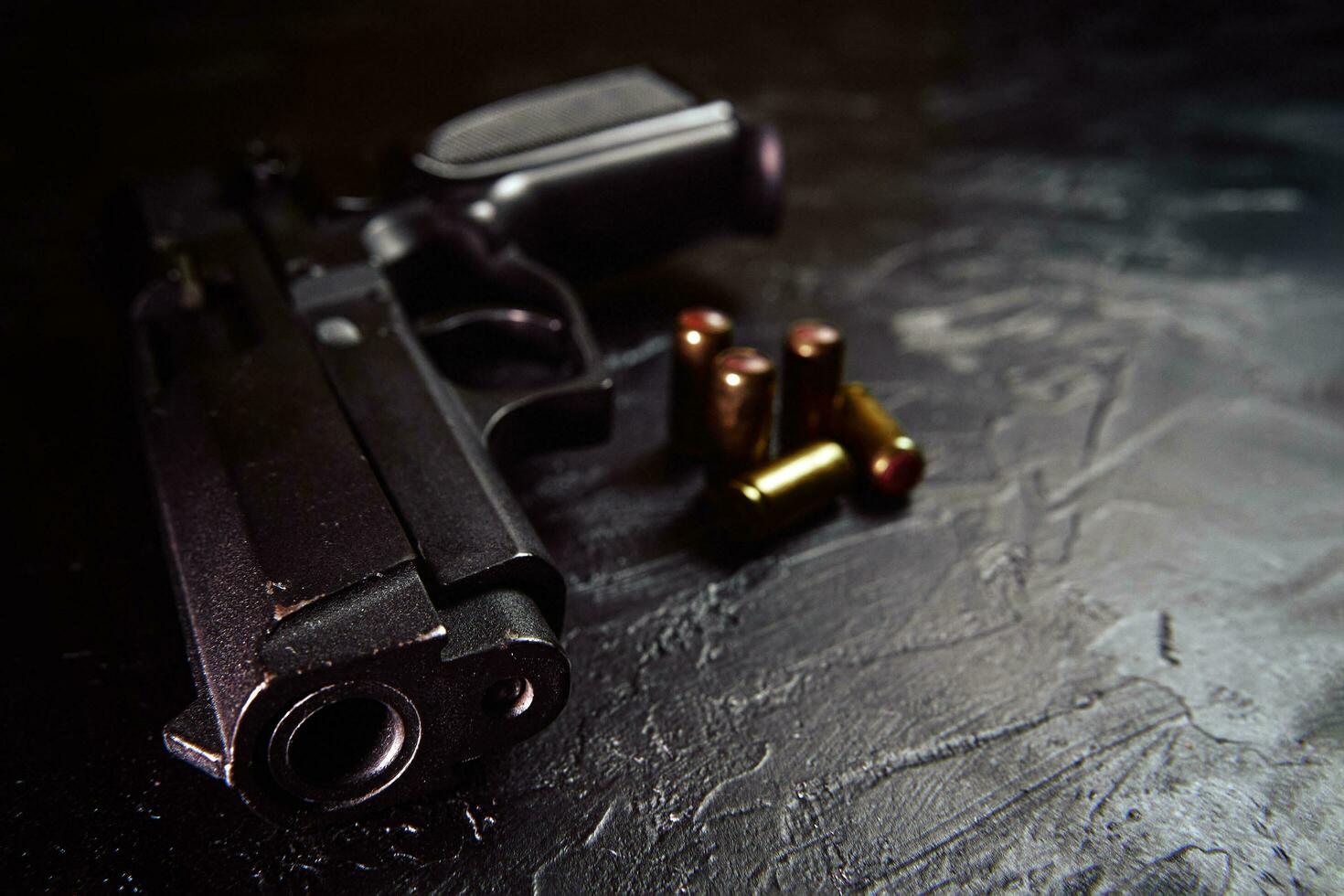 pistol med patroner på svart betongbord. foto