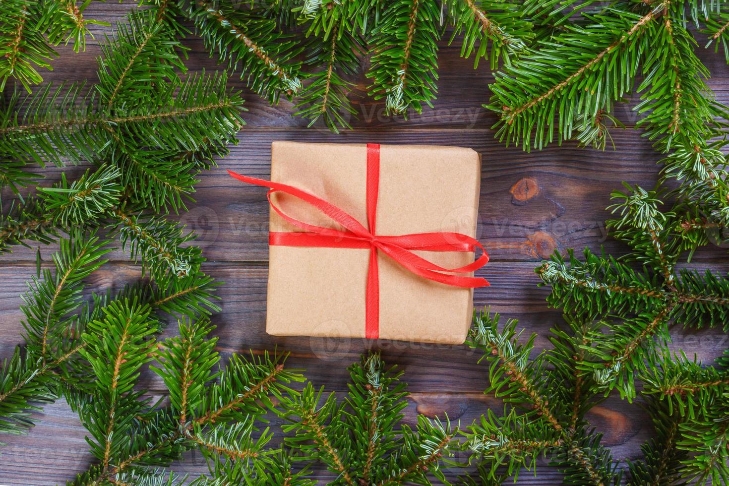 jul presenterar med röd band på mörk trä- bakgrund i en ram tillverkad av gran grenar med käppar. platt lägga stil foto